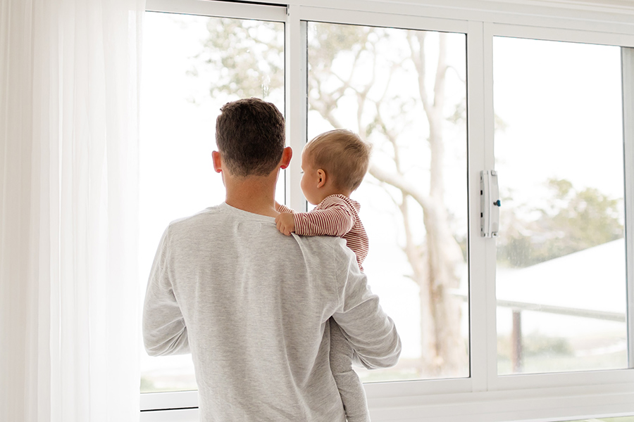 father holding child in front of a window