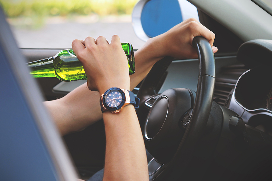 person drinking beer while driving